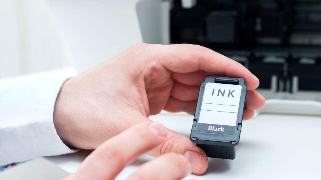 Person refilling a black ink cartridge in a printer