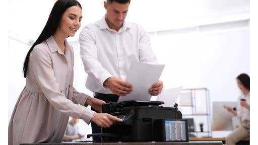 man and woman using a black desktop printer