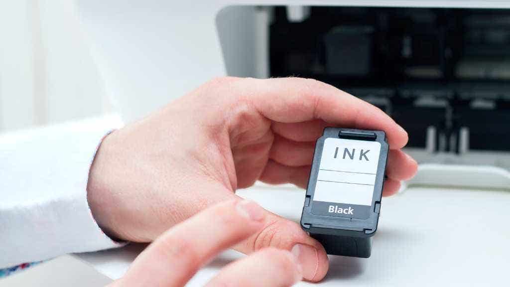 Person holding a black printer ink cartridge