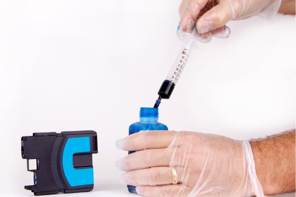 person refilling an empty ink cartridge