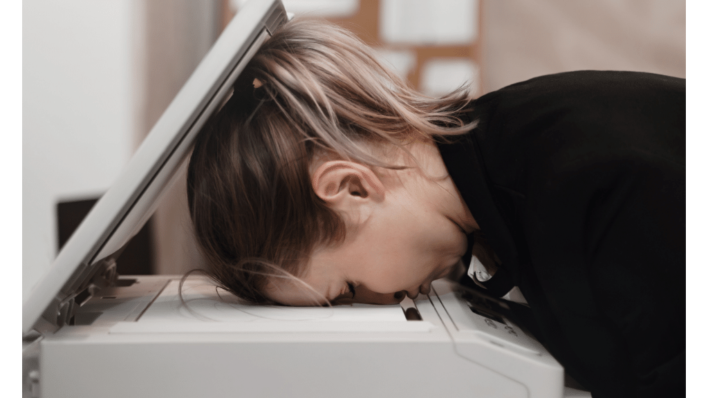 woman laying her head on a printer