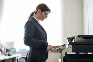 woman wearing a dark jacket using a printer