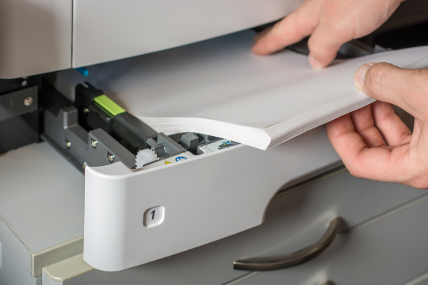 person loading paper in a printer