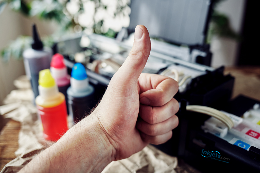 person with a gloved hand refilling ink tank printers